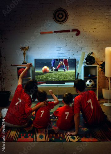 Konstfotografi Family watching soccer match on TV at home and cheering for goal together