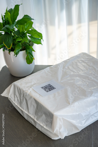 Packed parcel with QR code label ready for shipping placed on table at home. Delivery preparation completed with digital tracking and logistics concept.
