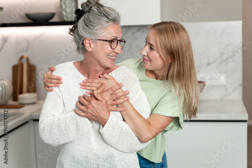 Tablou pe pânză Elderly mother and her adult daughter share a joyful moment at home together