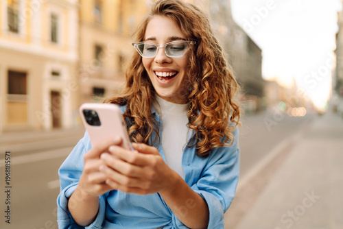 Foto A young woman stands with her phone on a city street on a sunny day