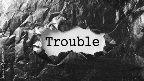 Word Trouble Written On White Paper Behind Torn Dark Silver Metallic Foil Background Concept Image
