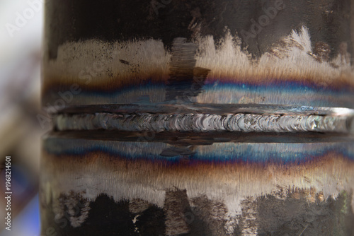 Close-up of a high-quality TIG welding root pass on a metal pipe. Detailed view of the weld bead, ripples, and heat-affected zone in industrial pipe fabrication.