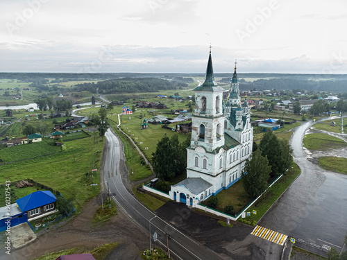 Atmospheric aerial drone shot of the Transfiguration Church (Spaso-Preobrazhenskaya Tserkov) in the village of Nizhnyaya Sinyachikha, Sverdlovsk Oblast, Russia, captured on a rainy summer day. The