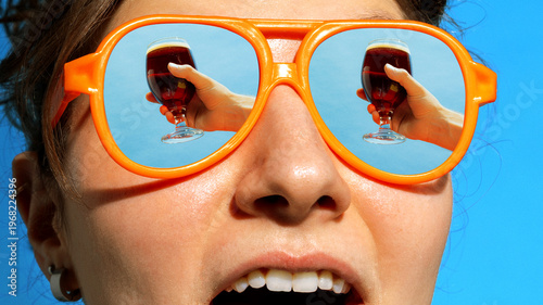 Canvas-taulu Woman in orange sunglasses with dark beer reflected in lenses under blue sky