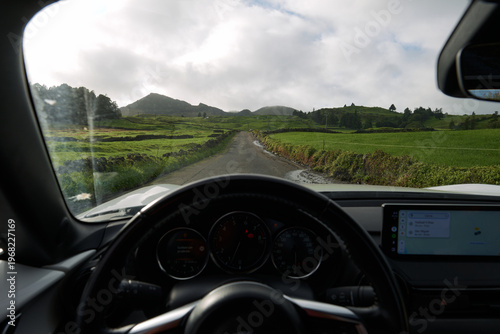 POV driver's perspective from car cockpit on small country road through green hills, Azores, Portugal