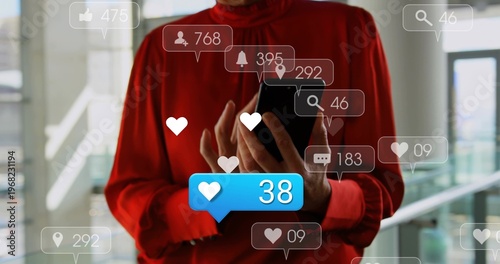 Woman in red blouse holding black smartphone tapping screen in glass atrium, with blue 38 icons