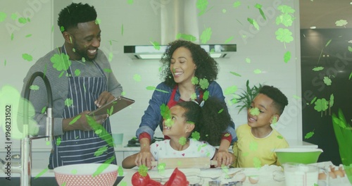 Gathering family of four preparing food at kitchen island, wearing striped apron and holding tablet