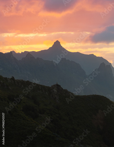 Aerial view of dramatic peaks pierce the sky as the sun sets, casting a warm glow on the rugged landscape, Santa Cruz de Tenerife, Canarias, Spain.