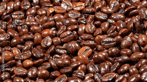 Horizontal rotating macro background of roasted coffee beans under hard lighting. Dramatic glossy texture for energetic cinematic cafe projects.