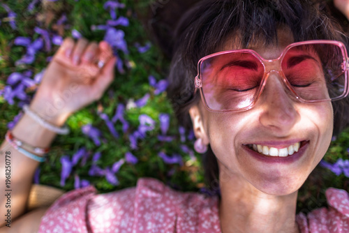 Summer mood. Young woman lies on green grass and flowers. Summer mood. Girl spends time outdoors. Face close-up. Enjoy nature and vacation.