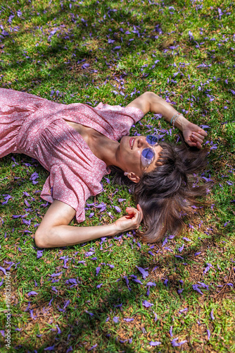 Young woman lying on the field in green grass. Summer mood. Girl spending time Outdoors. Enjoy nature. Top view.