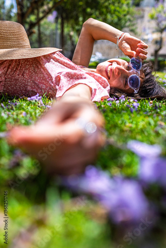 Summer mood. Young woman lying on green grass and flowers. Summer mood. Girl spending time outdoors. Enjoy nature and vacation.