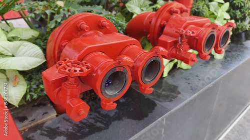 Modern City infrastructure features red fire hydrant installation among plants for urban safety. Asian street landscaping uses Modern City firefighting equipment to protect public garden environment.