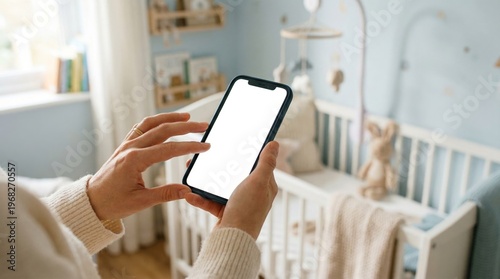 Woman holding smartphone with blank screen in bright baby nursery near crib and toys. Concept of parenting, childcare, baby monitoring, mobile app, family life, home technology. Generative AI.