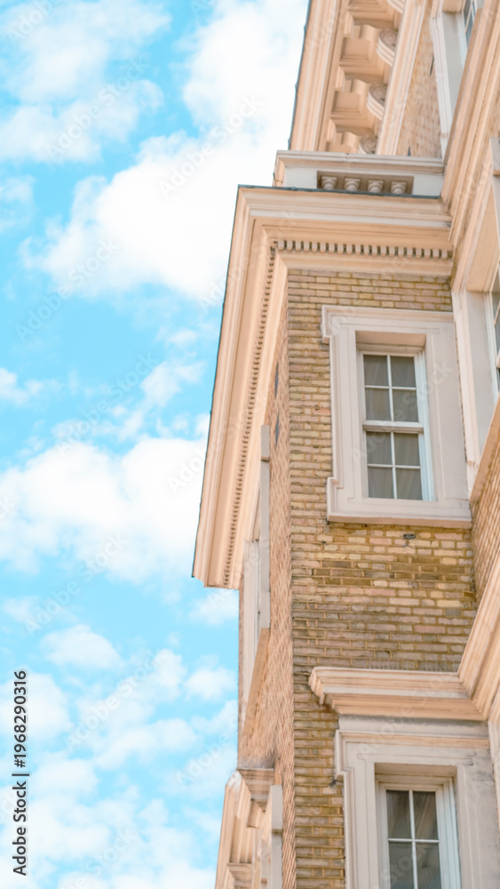 Fototapeta premium Corner view of historic brick building against a bright blue sky