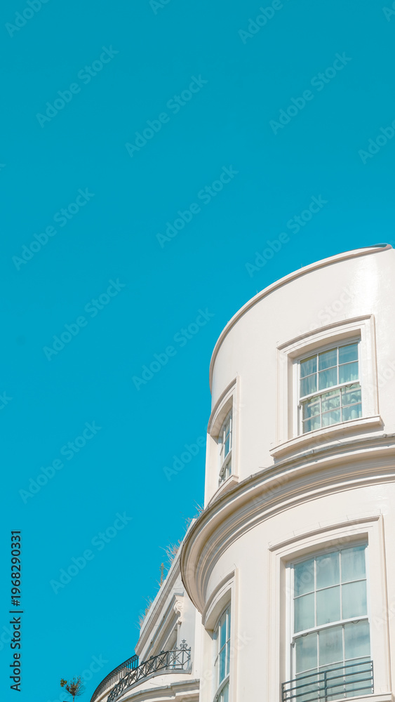 Obraz premium Curved white building facade against clear blue sky in urban setting