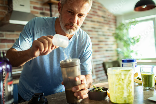 Tableau sur toile Middle aged man preparing protein shake in home kitchen