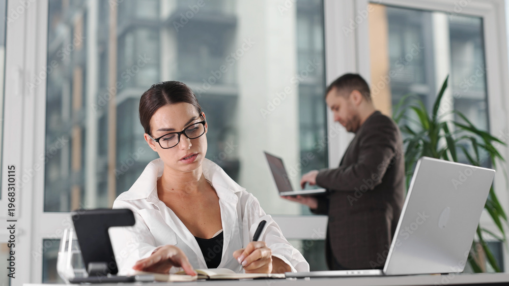 Fototapeta premium Woman using laptop for business tasks in modern office space. Corporate concept. 