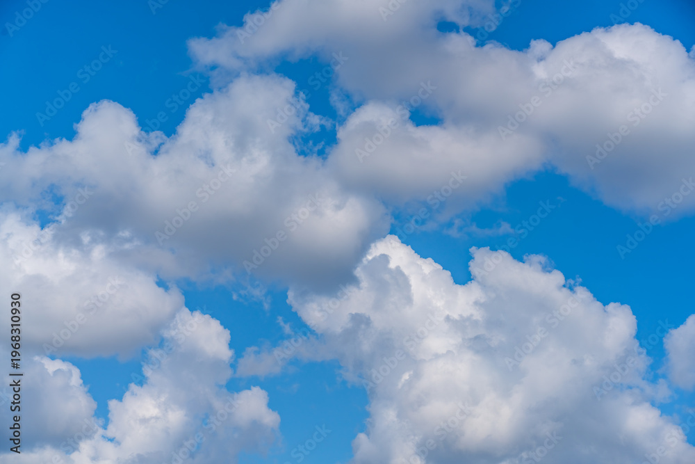 Fototapeta premium Blue sky with scattered white clouds forming soft shapes, creating minimal and airy composition. Concept of freedom, weather, calm atmosphere