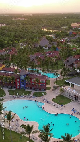 Aerial flight above luxury resort with swimming pool tropical beach at sunset