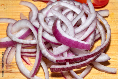 Close up of finely chopped sliced red onion salad vegetables on wooden chopping board