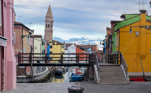 Colorful canal street with boats and bell tower