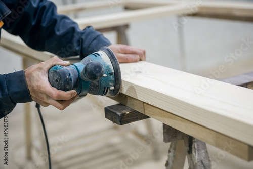 Tableau sur toile Worker sanding the wooden surface. In the hand of the power tool.