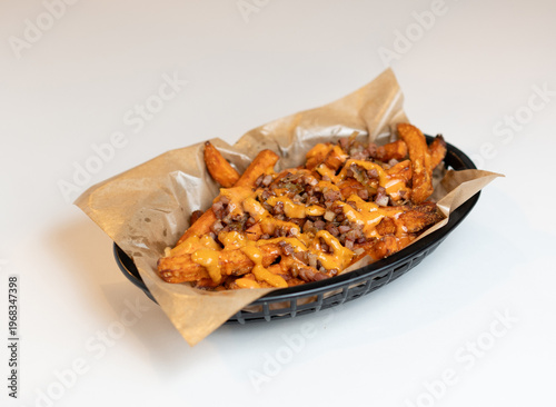 Canvastavla Plate of loaded fries with cheese, meat, and onions served in a black basket on