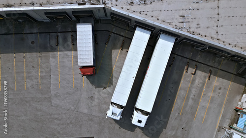 Photography Two large trucks enter a distribution warehouse, their engines humming as they maneuver into designated spots