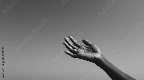 black and white photograph depicting hand reaching towards sky symbolizing hope and faith