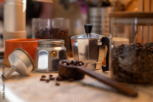 Ingredients for making coffee. Moka coffee maker, coffee grinder with coffee beans are on the table of a cozy kitchen.