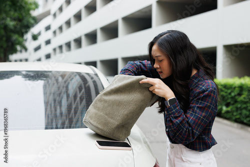 Tableau sur toile Young Asian woman meticulously searching through her handbag for missing items o