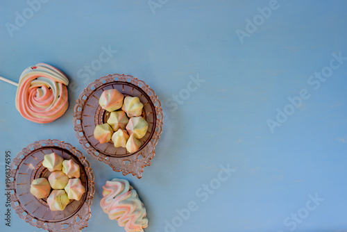 Colorful marshmallows in a bowl on blue wooden background.