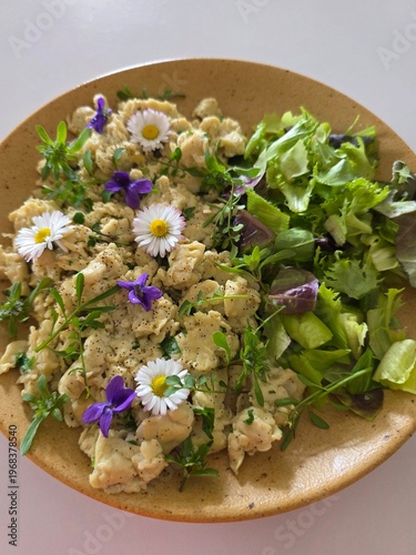 Healthy gourmet salad with edible flowers, daisies and fresh greens.