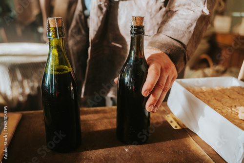 Konstfotografi A person holding a bottle of dark homemade wine or liqueur with a cork