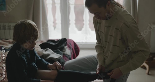 Man puts warm clothes on child. Dad help child to dress at home. 4K 10-bit