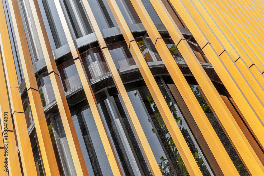 Obraz premium Vertical yellow louvers covering curved building facade with windows