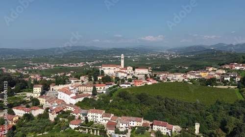 Aerial view of Chiesa Parrocchiale dei Santi Fermo e Rustico in Colognola ai Colli, Italy. Drone shot of the historic church and bell tower overlooking the scenic Veneto landscape and vineyards.