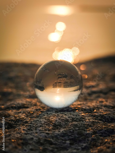 golden globe , earth, world on the beach, The crystal ball is surrounded by bokeh from the sunset.
