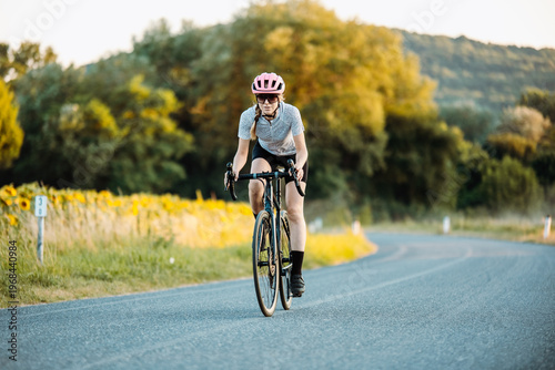 Solitary Female Cyclist Enjoying Peaceful Ride Through Expansive Countryside Under Evening Sunlight