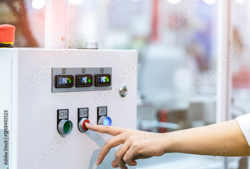 Принти на полотні Engineer hand pressing red shutdown button on temperature control cabinet, industrial heat regulation system in factory