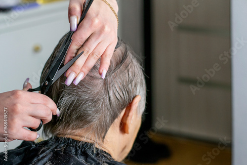 Hairdresser Trimming Grey Hair Of Old Woman