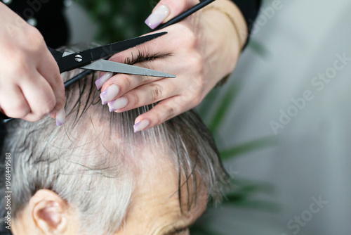 Hairdresser Trimming Grey Hair Of Old Woman