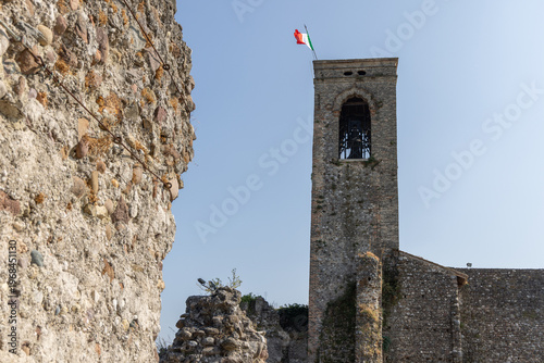 Historic castle ruins and tall belfry in Cavriana Lombardy Italy seen beside a rough stone wall, wide view highlights eroded textures surviving fortifications open sky and the quiet presence