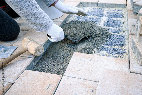 Worker hands spreading gravel with a trowel for outdoor patio paving