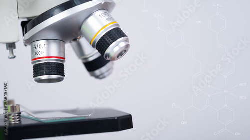 Close up microscope objective lenses with molecular structure overlay in laboratory environment. Concept of biotechnology research, microbiology analysis and pharmaceutical science innovation.