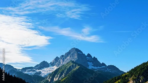 a distant peak surrounded by thin moving clouds, gentle daylight atmosphere 