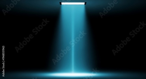 A single beam of blue light illuminates a dark space from above, creating a spotlight effect on the floor.