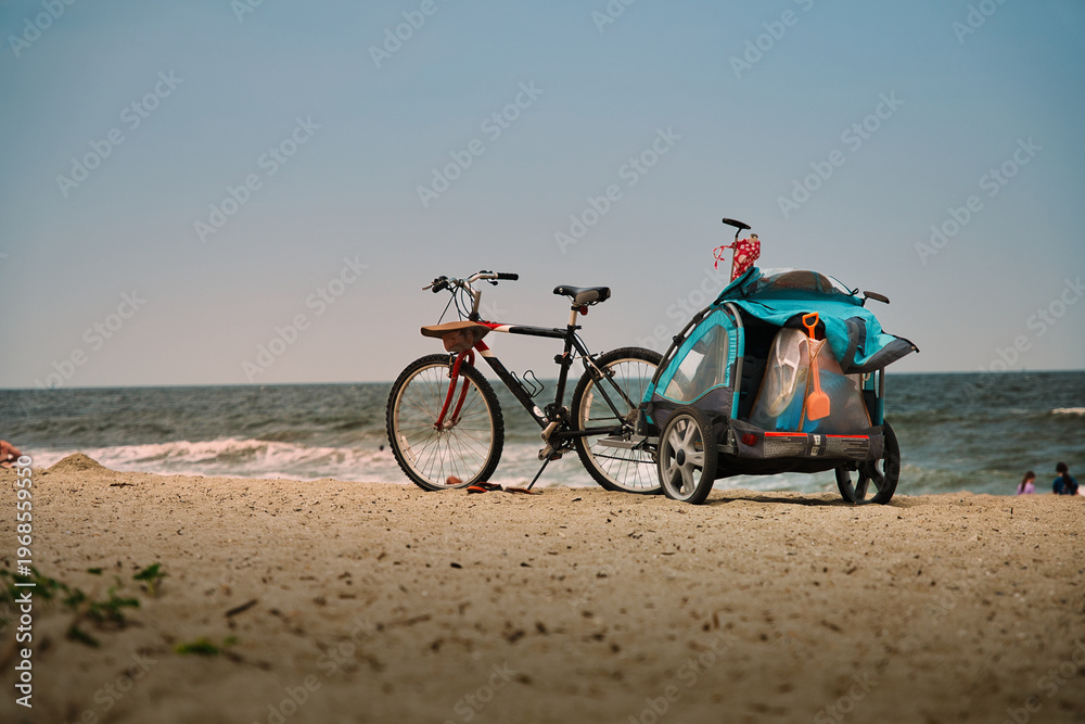 Fototapeta premium Family Beach Day with Bicycle and Child Trailer on Florida Coastline – Active Summer Lifestyle