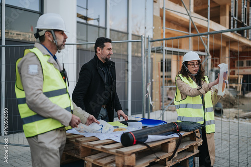 Fotografie Construction engineers review plans and blueprints at an active building site